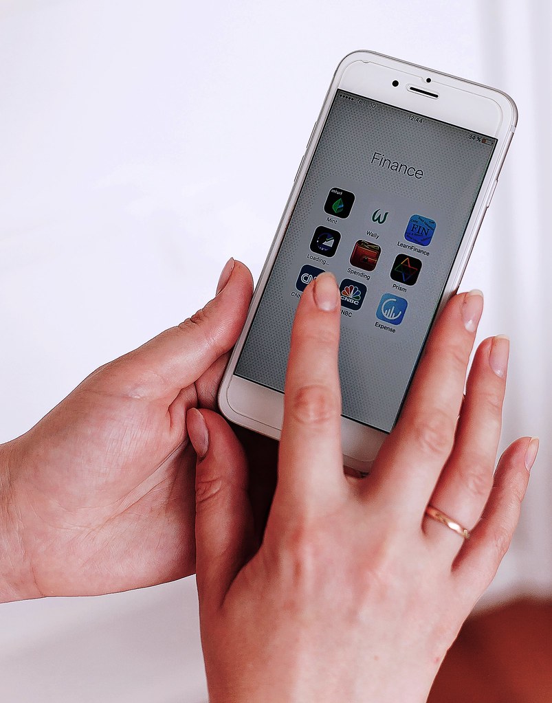 Hands holding a smartphone showing a screen of app icons